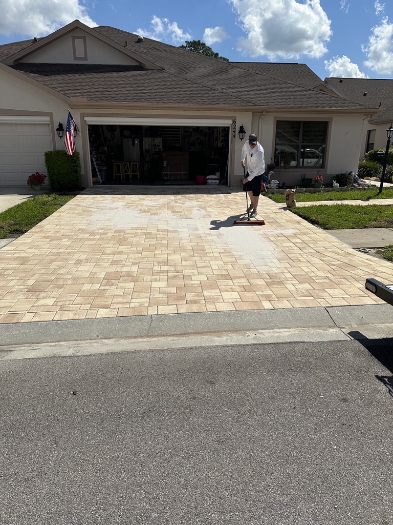 Lati-Dudes technician sweeping joint sand into a freshly cleaned paver driveway